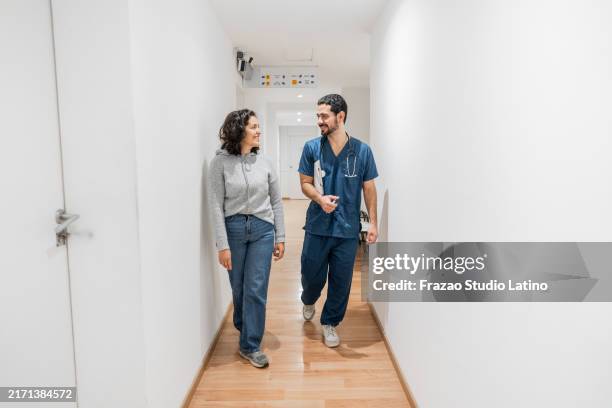 doctor and patient talking and walking in a hospital - doctor stethoscope patient whole body stock pictures, royalty-free photos & images
