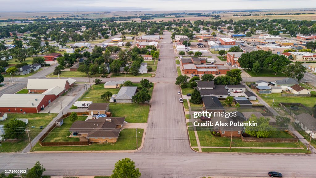 Main street stretching along rural residential neighborhood of Garden City, Kansas. Vast farmlands nestled in the distance