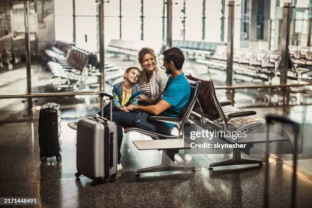 feliz familia hablando mientras espera su transporte en una estación. - estación de autobús fotografías e imágenes de stock