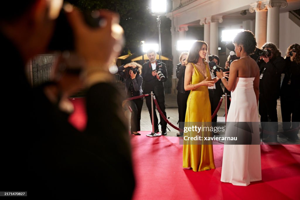 Young celebrity and media host conversing on red carpet