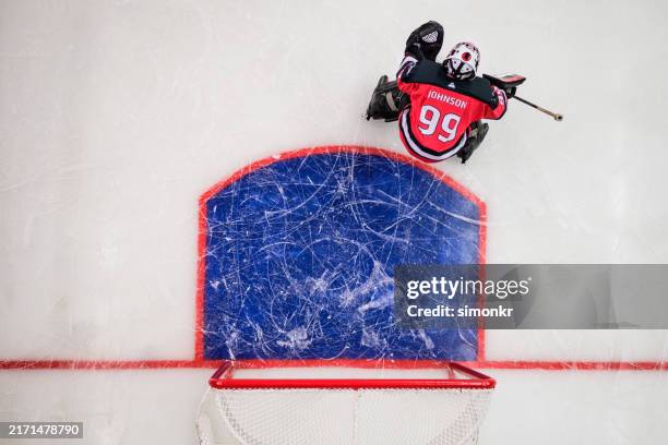 draufsicht auf den eishockey-torwart, der das tor verteidigt - eishockey tor stock-fotos und bilder