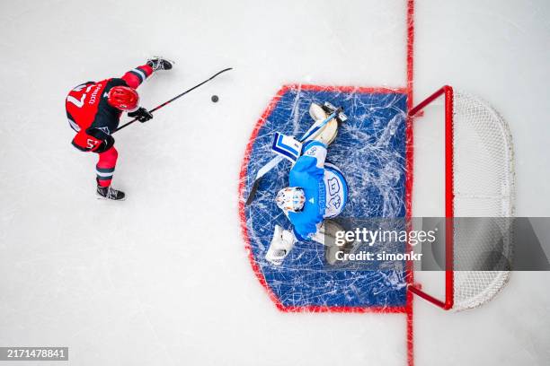 overhead view of ice hockey forward attempting a goal against the goalie - personal accessory stock pictures, royalty-free photos & images