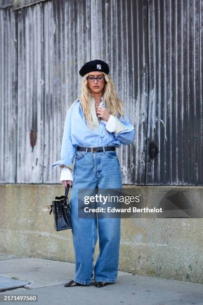 Emili Sindlev wears New York Yankees black Beret, gold layered necklace, light blue buttoned up long sleeve layered shirt, black leather belt, light...
