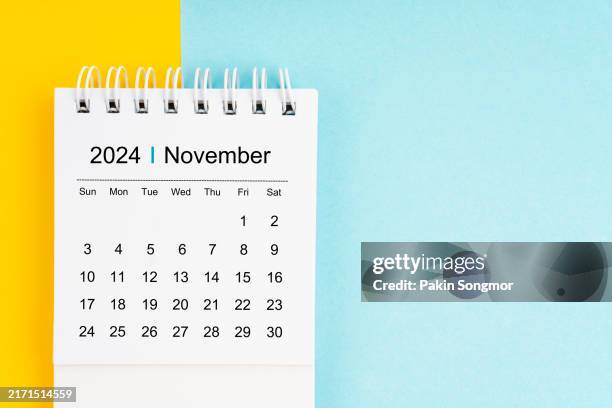 november 2024 desk calendar on blue and yellow color background, position with copy space. - november stock pictures, royalty-free photos & images