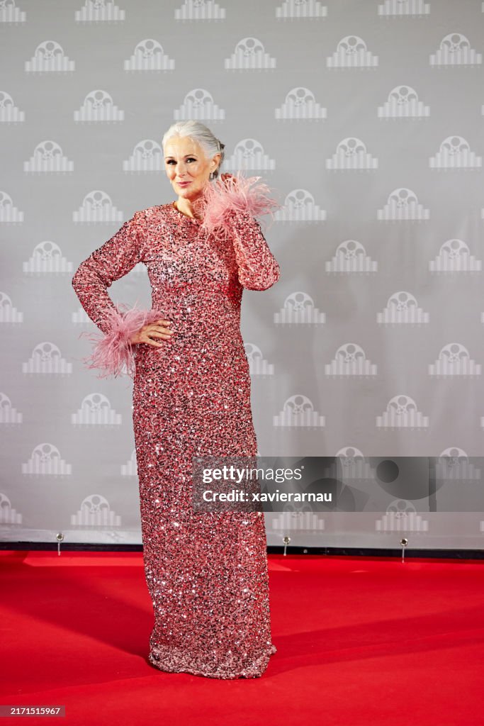 Mature celebrity posing against step and repeat wall