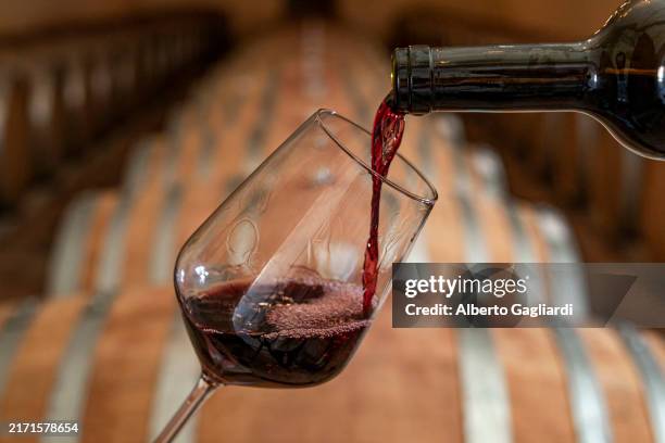 pouring red wine into the glass in the cellar - wine glass stock pictures, royalty-free photos & images