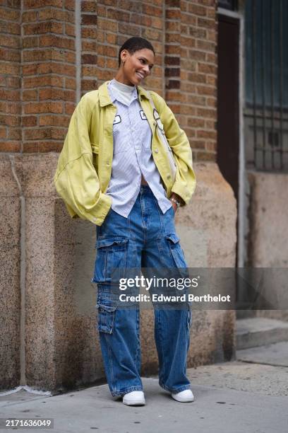 Guest wears white turtleneck shirt, light blue button up long sleeve shirt, light green yellow oversized leather jacket, silver earrings, silver...