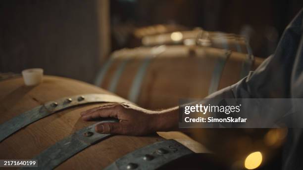 winemaker inspecting barrel in cellar - basement cellar stock pictures, royalty-free photos & images