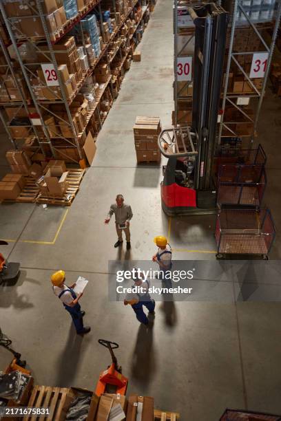 vista superior de un gerente maduro hablando con trabajadores manuales en el almacén de distribución. - trabajador de almacén fotografías e imágenes de stock