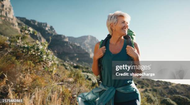 hiking, relax and senior woman with smile in forest, woods or nature for peace, trekking or outdoor adventure. mountain view, retirement or hiker in park for travel or wellness on holiday vacation - mature women stock pictures, royalty-free photos & images