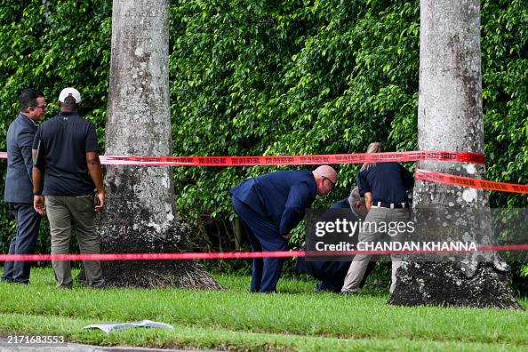 Law enforcement officials work near the crime scene outside the Trump ...