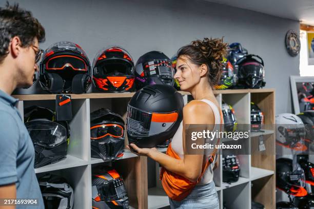 young couple shopping for motorcycle helmets in a moto shop - crash helmet stock pictures, royalty-free photos & images