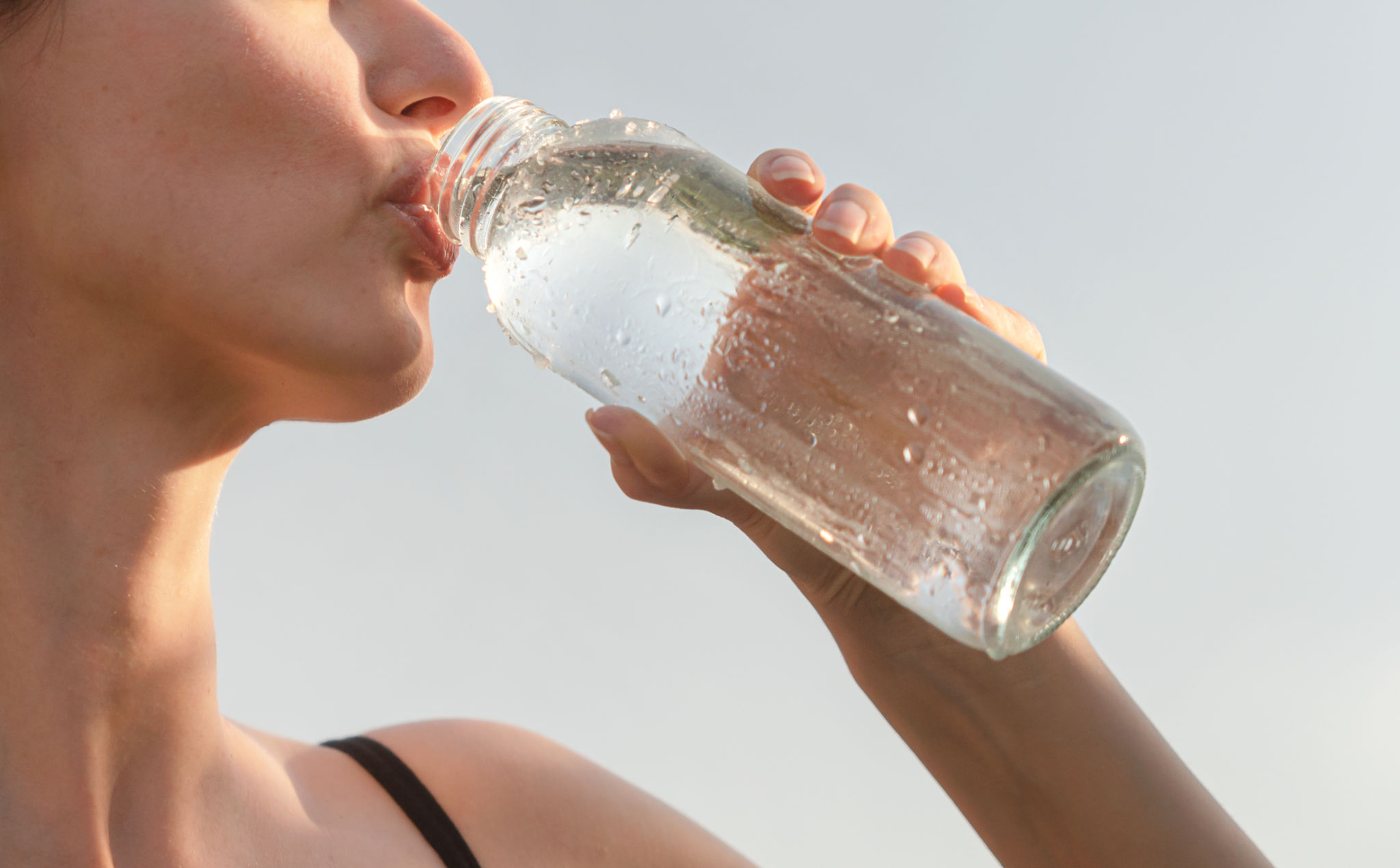 Mujer bebiendo agua fresca de una botella Mujer bebiendo agua fresca de una botella