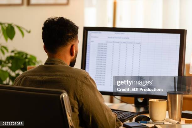 unrecognizable young adult male works on his computer - spreadsheet stockfoto's en -beelden