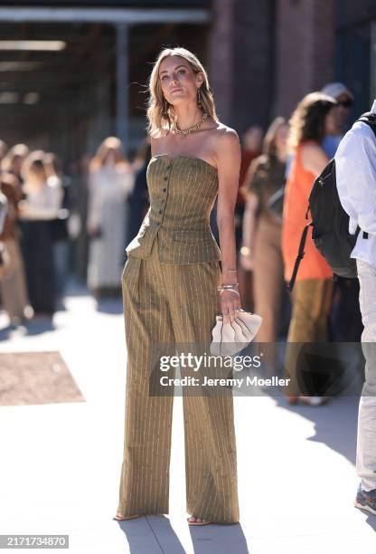 Fashion Week guest is seen wearing gold dangling earrings, a gold necklace, a black buttoned strapless olive top with white stripes from Ulla...