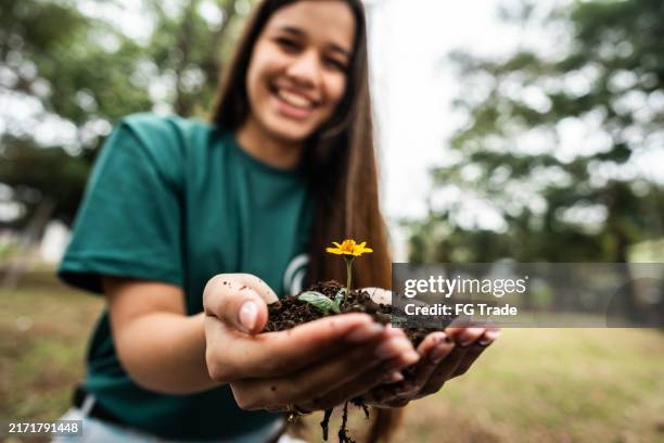 close-up of a woman holding sprout young plant outdoors - earth day stock pictures, royalty-free photos & images