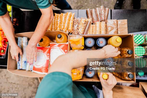 des bénévoles organisent des articles pour les dons à l’extérieur - urne de donation photos et images de collection