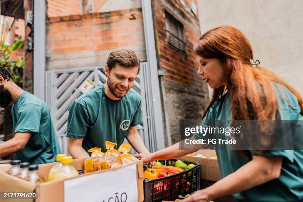volunteers arranging items for donation outdoors - food distribution stock pictures, royalty-free photos & images