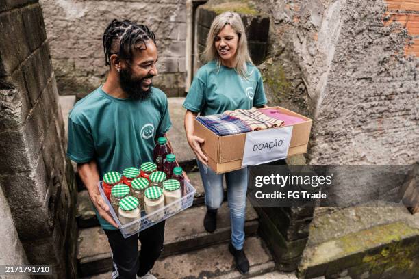 volunteers carrying a donation box outdoors - food distribution stock pictures, royalty-free photos & images