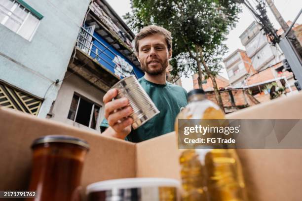 mid adult man organizing items to donation - food distribution stock pictures, royalty-free photos & images