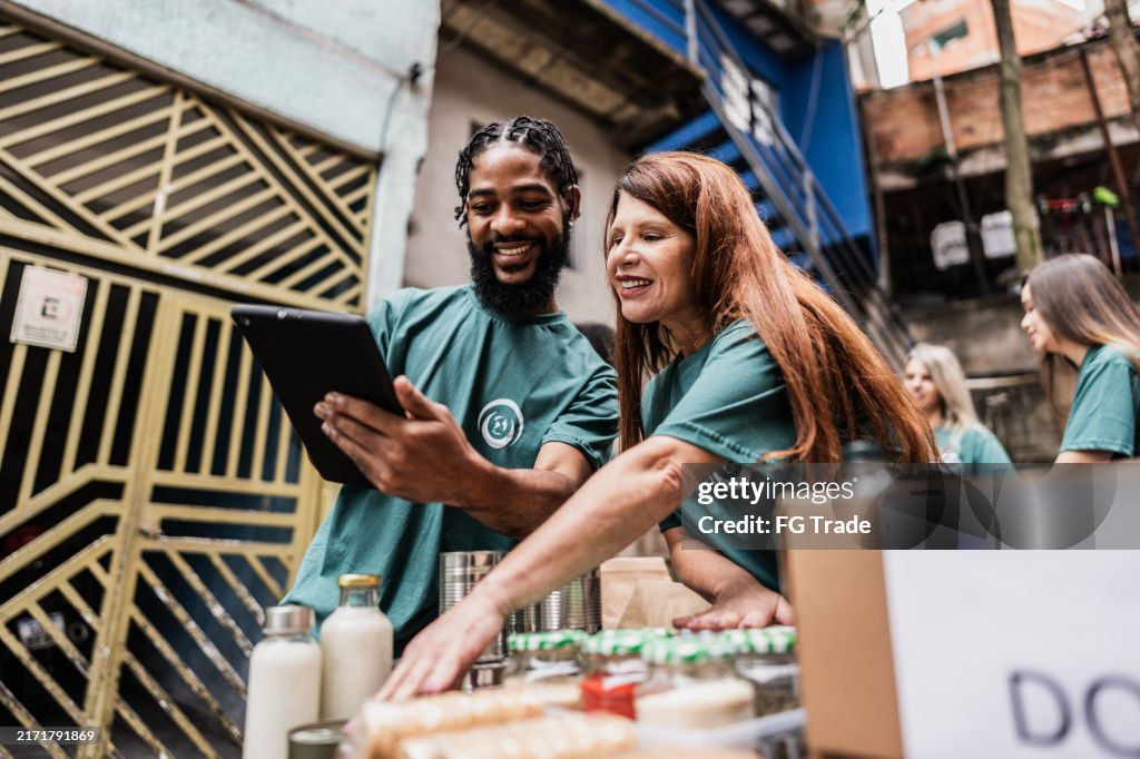 Volunteers using digital tablet during donation outdoors