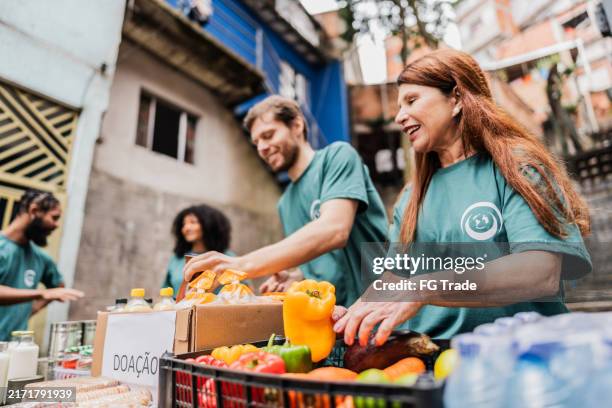 volunteers arranging items for donation outdoors - food distribution stock pictures, royalty-free photos & images