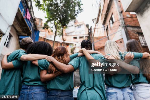 volunteers embracing outdoors - maatschappelijke verantwoordelijkheid stockfoto's en -beelden