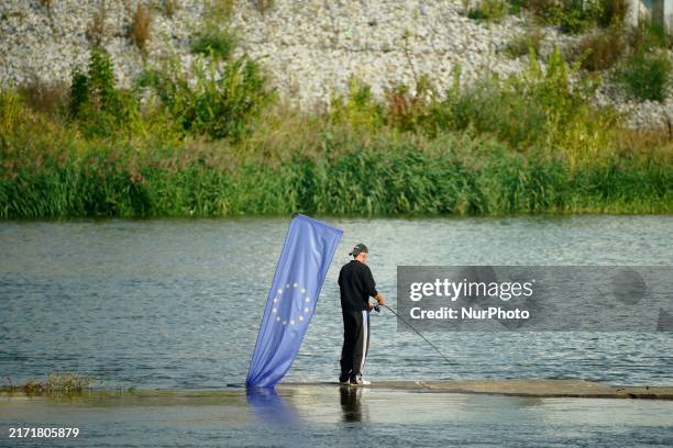 Man is seen fishing next to a partially submerged EU flag in the river Oder in Slubice, Poland on 17 September, 2024. The German state of Brandenburg...
