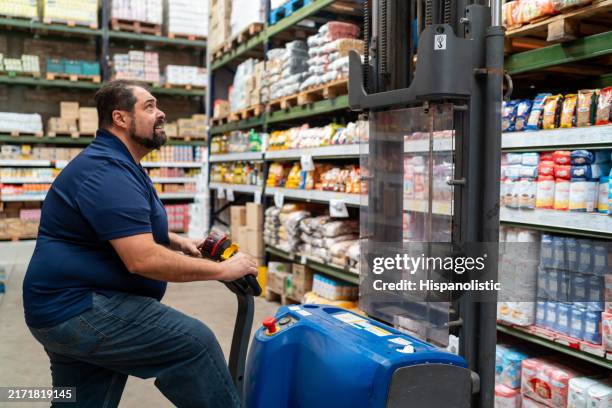 employee working at a wholesale supermarket using a forklift while restocking shelves - grocery store worker restocking shelves stock pictures, royalty-free photos & images