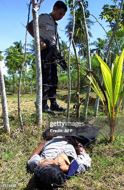 An Indonesian policeman stands near a body of an alleged member of the rebel Free Aceh Movement at Krueng Kalee in Aceh Besar, 17 July 2003....