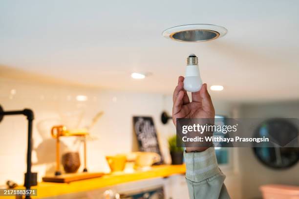 male hand is installing a led light bulb into a ceiling can fixture. - installing ceiling light fixture stock pictures, royalty-free photos & images