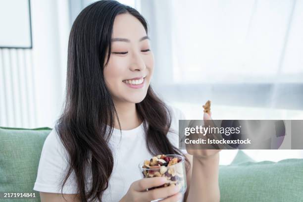 Beautiful Young Woman Holding Nuts Happy With Big Smile Doing Ok Sign Thumb Up With Fingers Excellent Sign, Bildbanksbilder