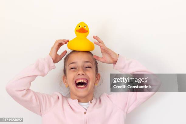 playful teenage girl holding rubber duck toy on her head - rubber duck stock pictures, royalty-free photos & images
