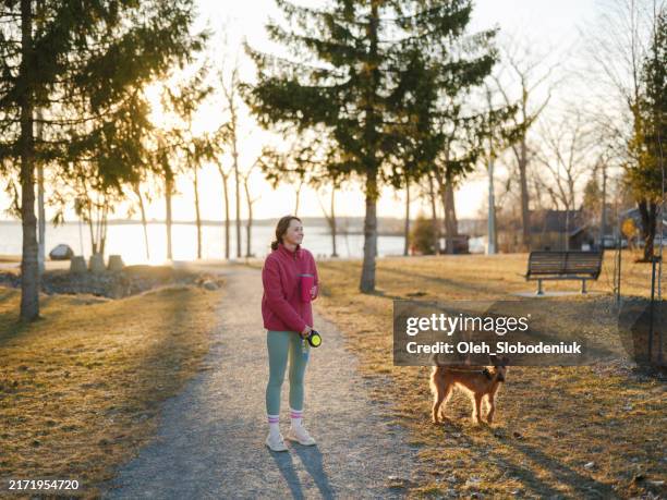 woman on walk with dog in springtime at sunset - city break stock pictures, royalty-free photos & images