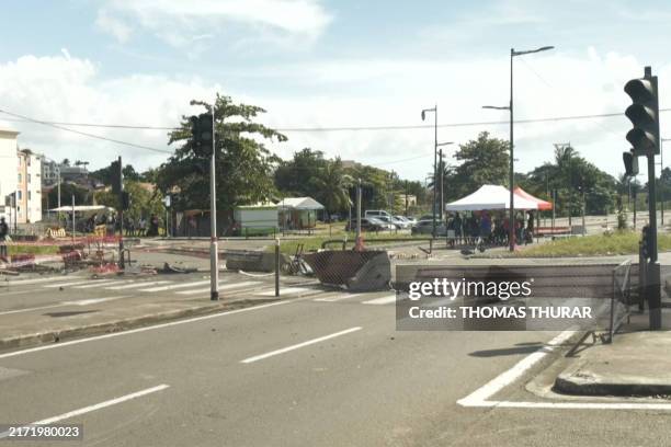 An image taken from an AFP video released on September 17, 2024 shows people standing at a road blockage in Fort-de-France in the French Caribbean...