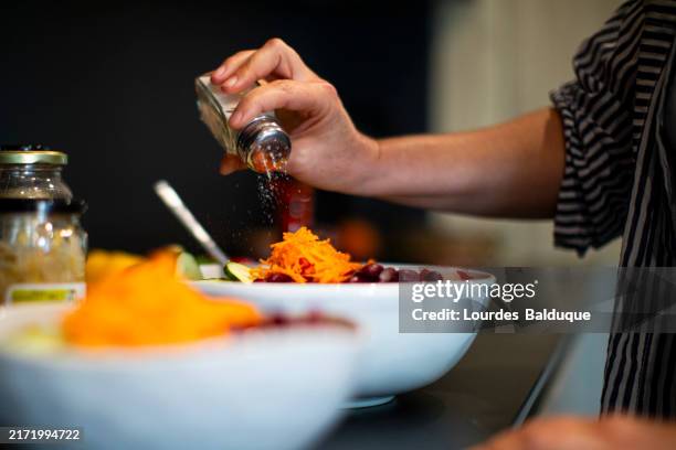 adding salt to vegan food at home - salado fotografías e imágenes de stock
