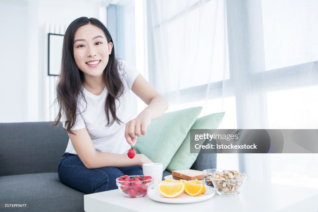 Woman having breakfast in bed. Big continental breakfast. Asian caucasian woman smiling looking at camera.
