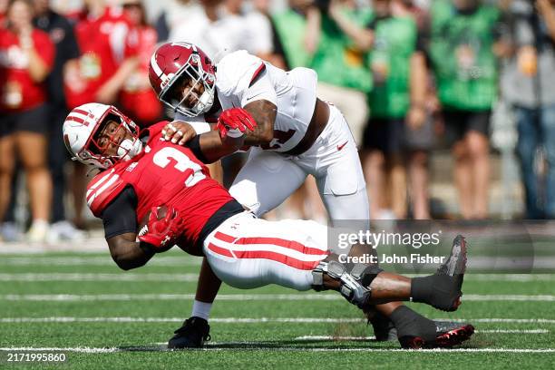 Tawee Walker of the Wisconsin Badgers catches a pass over the middle and is tackled by Jihaad Campbell of the Alabama Crimson Tide in the first...