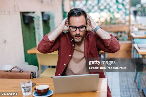 mann ungläubig schaut auf laptop in einem café. - schockiert stock-fotos und bilder