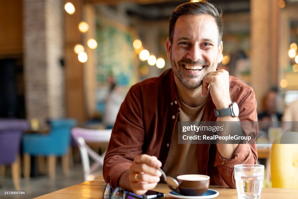 Laughing man savoring coffee moment in a cafe.