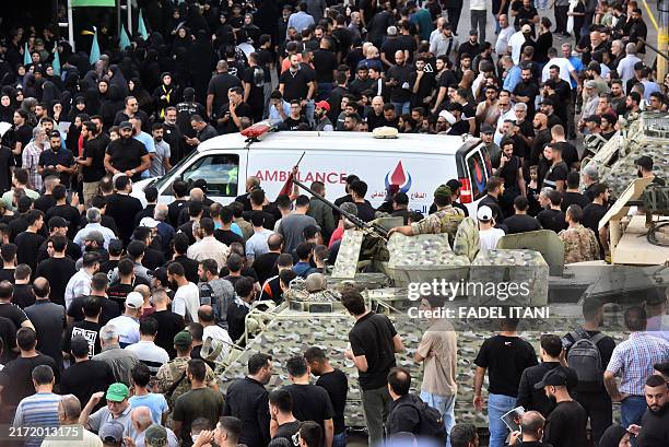 Lebanese army soldiers stand guard as an ambulance arrives after a reported device explosion occurred during the funeral of people killed when...