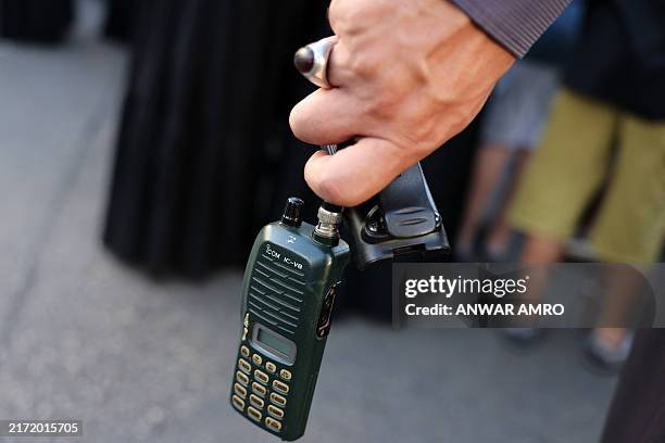 Man holds an Icom walkie talkie device after he removed the battery during the funeral of persons killed when hundreds of paging devices exploded in...