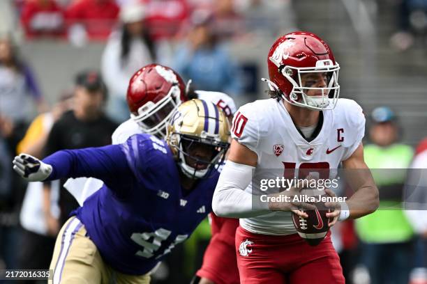 John Mateer of the Washington State Cougars rolls out of the pocket with defensive lineman Deshawn Lynch of the Washington Huskies in pursuit during...