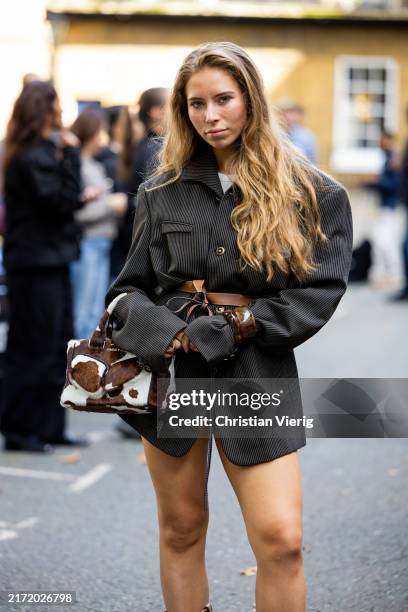 Guest wears grey blazer, mini skirt, cow print brown white bag outside Ahluwalia during London Fashion Week September 2024 on September 14, 2024 in...