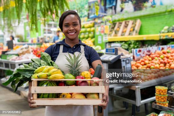 empleado de una tienda con una cesta de comestibles en la frutería - mercado colombia fotografías e imágenes de stock