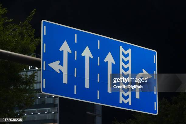 multi-lane road sign at night - multi directional arrow stock pictures, royalty-free photos & images
