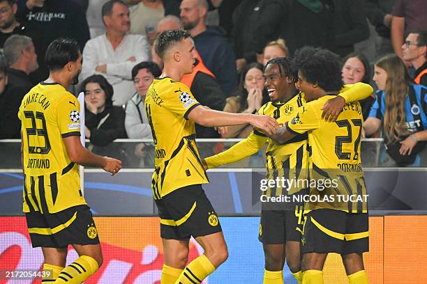 Borussia Dortmund's English forward Jamie Bynoe-Gittens celebrates with teammates after scoring his team's first goal during the UEFA Champions...