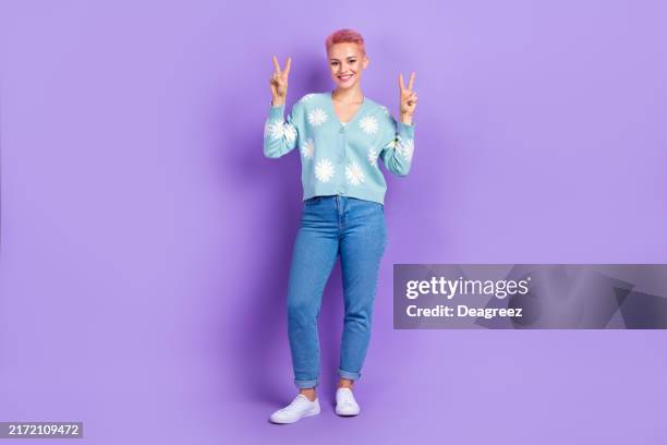Full length photo of cheerful pretty woman wear blue cardigan daisy print show v-sign hello peace symbol isolated on violet color background