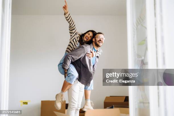 happy couple with arms stretched out enjoying in new home - proprietario di casa foto e immagini stock