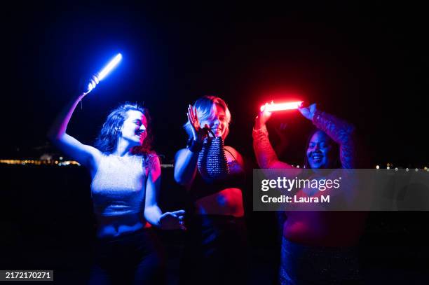cool women dancing with laser swords at beach party - laser sword stock pictures, royalty-free photos & images